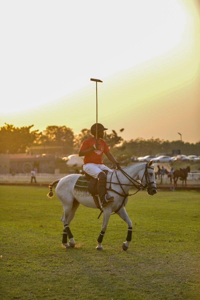 A polo player riding a white horse on a field